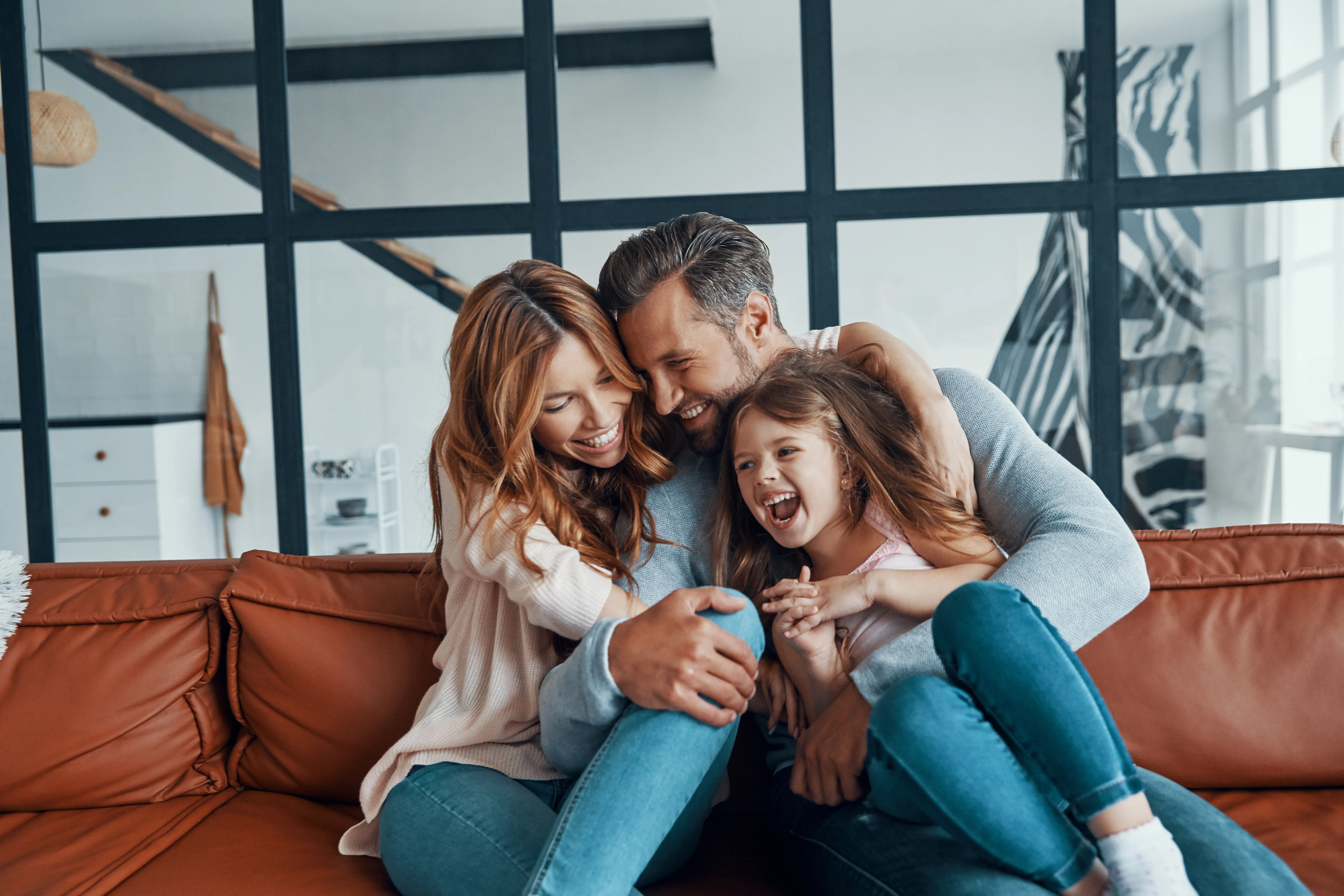 Parents and their daughter laughing together on a sofa